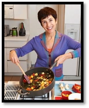 Smiling Leslie Bonci cooking veggies in a frying pan