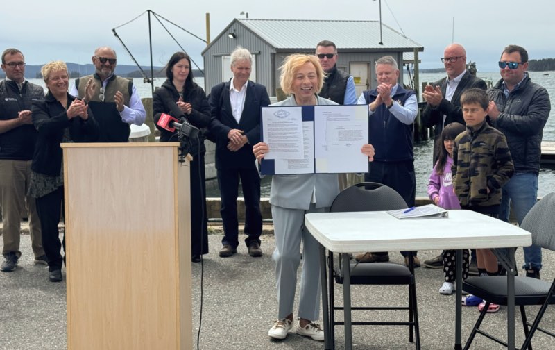 Governor Mills holds up her Executive Order on a dock in Stonington