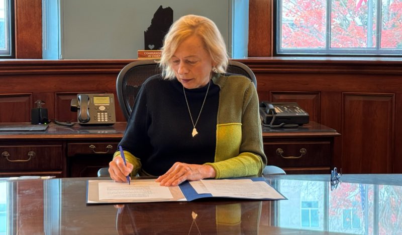 Governor Mills signs the Executive Order at her desk